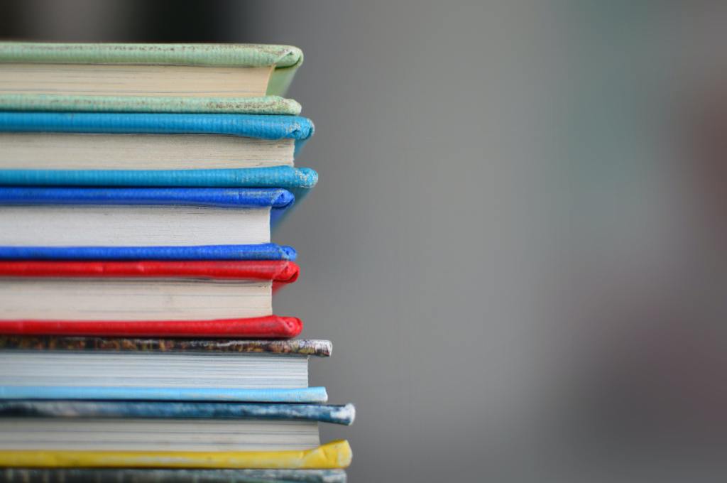 Image shows a pile of hardback books